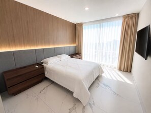 Una camera da letto moderna con un letto grande, un comodino, una TV a parete e una finestra con tende.