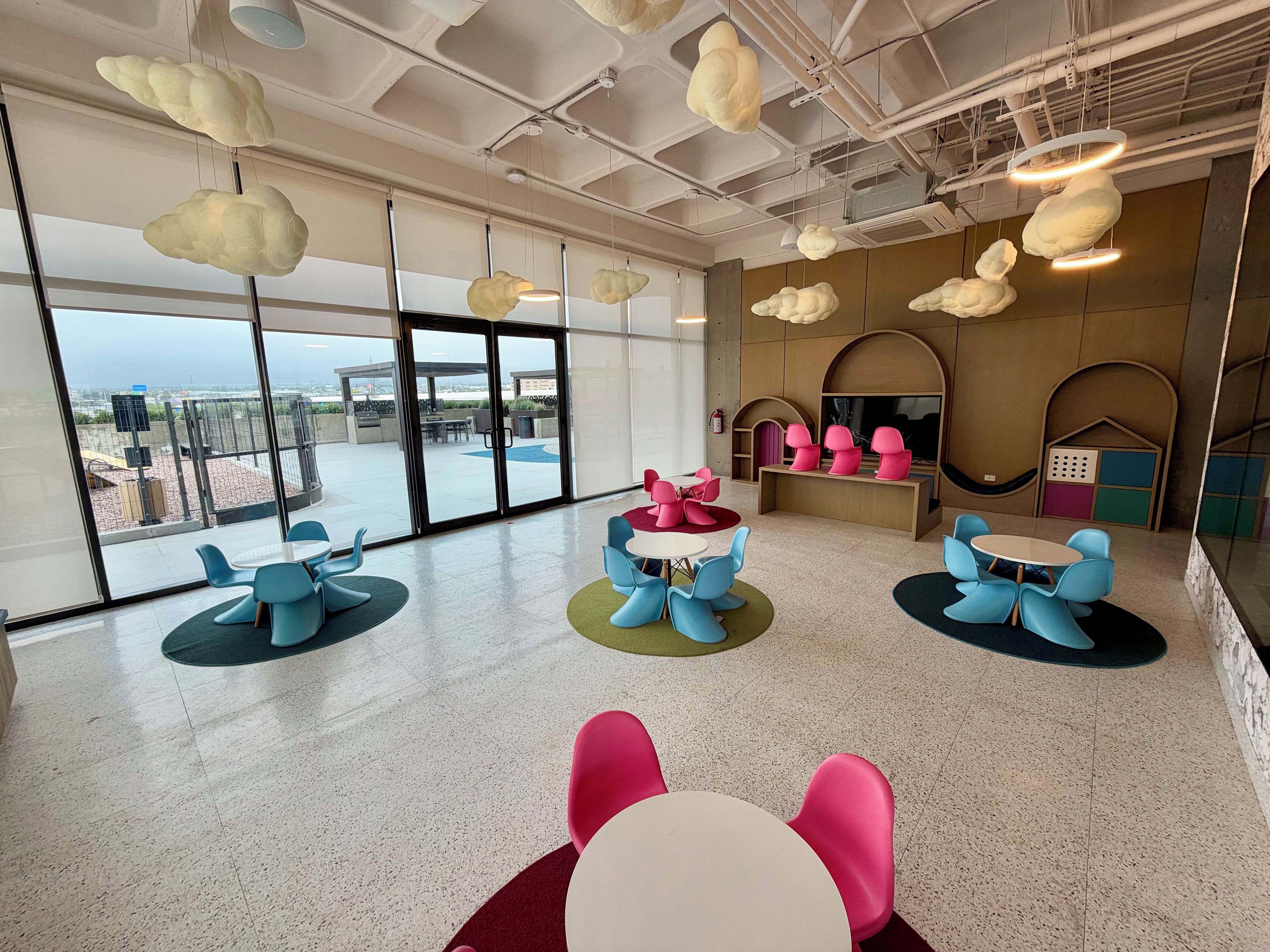 Un intérieur moderne avec des tables et des chaises rondes, de grandes fenêtres et une vue sur l’extérieur.