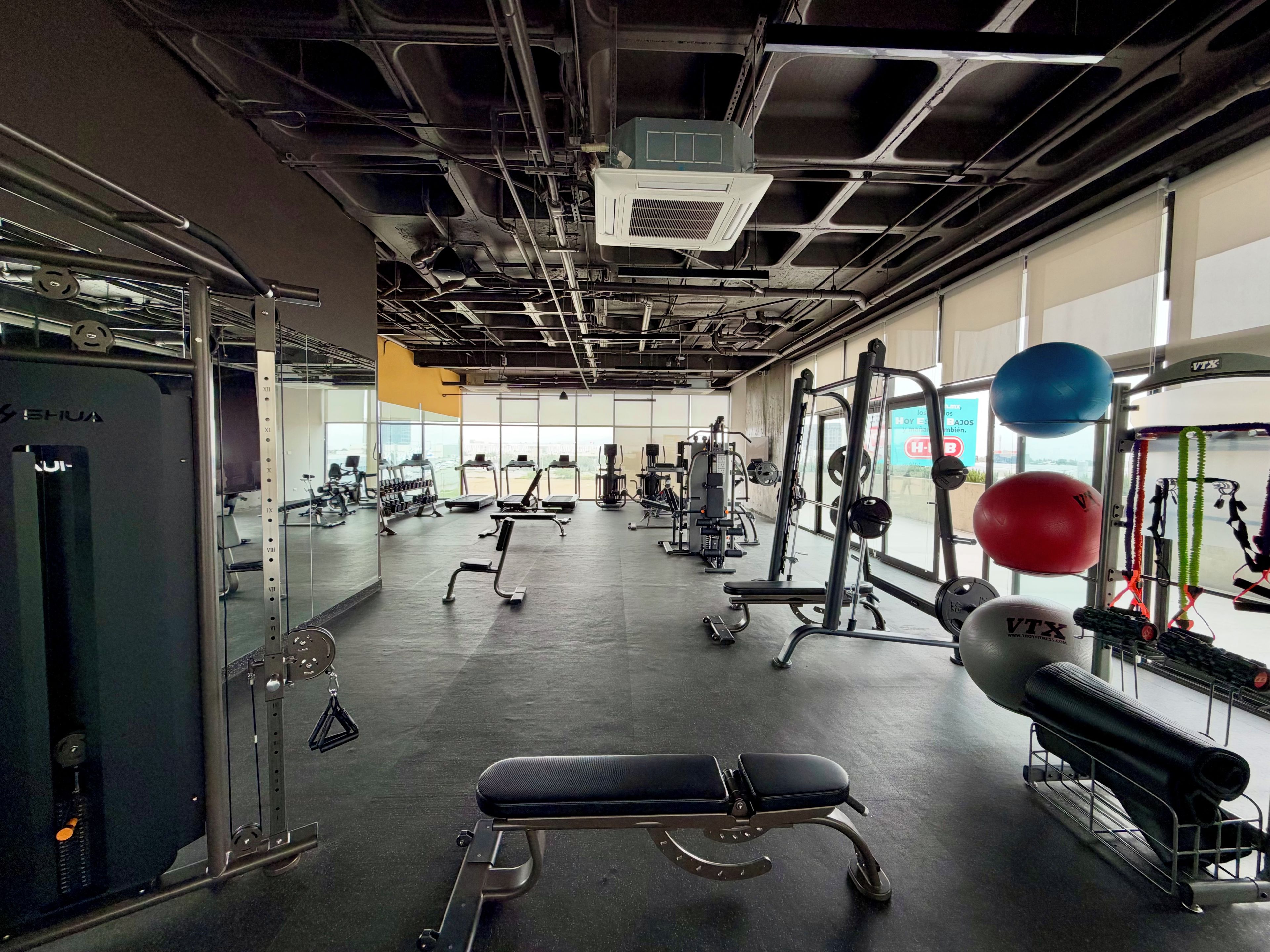 Une salle de sport équipée de divers appareils d’exercice, notamment un banc, des machines de musculation et des ballons d’exercice.