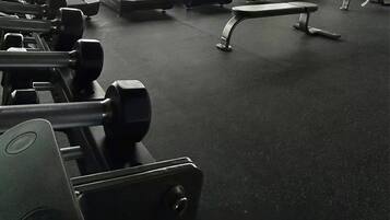 A gym with treadmills, weight machines, and dumbbells.