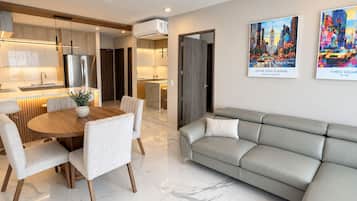 A modern living room with a dining area, a grey sofa, and a kitchen in the background.