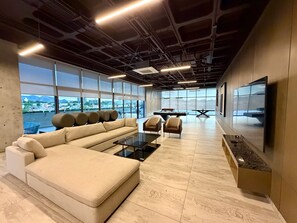 A modern lounge with a sofa, chairs, a pool table, and a large TV. - Vrbo Property (Saltillo)