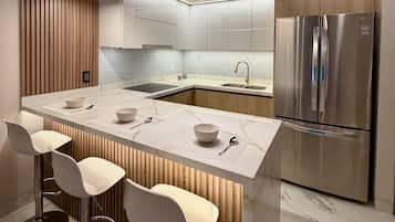 A modern kitchen with a central island, bar stools, stainless steel appliances, and wooden paneling.