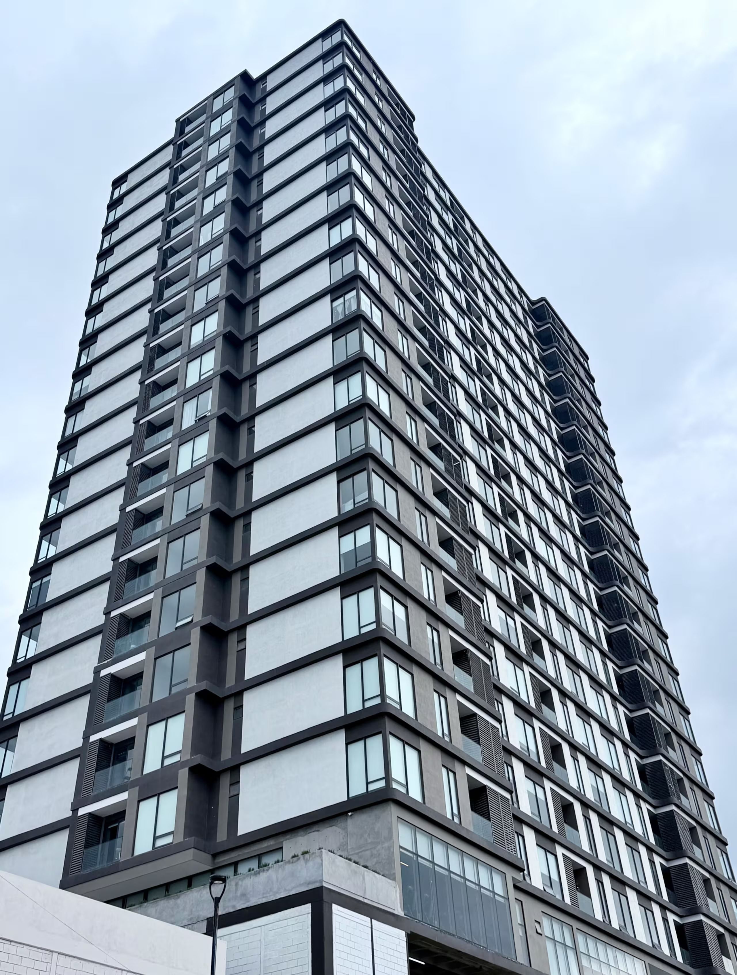 Un edificio de gran altura con un diseño arquitectónico moderno, que presenta una cuadrícula de ventanas y balcones.
