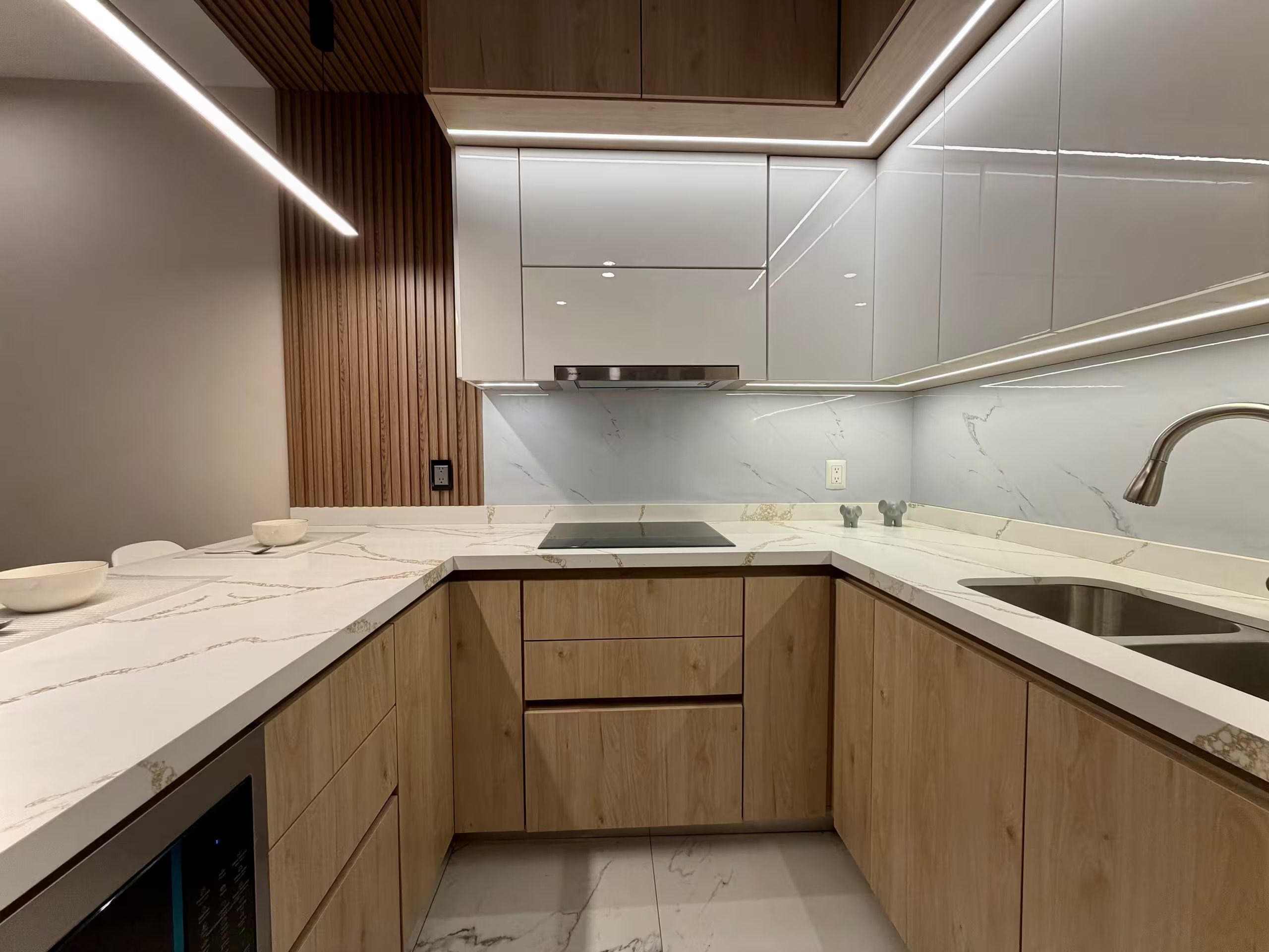 A compact kitchen with wooden cabinets, a marble countertop, and a stainless steel sink.