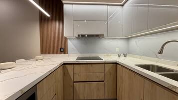 A compact kitchen with wooden cabinets, a marble countertop, and a stainless steel sink.
