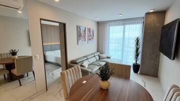 A modern living room with a dining area, a sofa, a TV, and a large window.