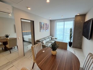 A modern living room with a dining area, a sofa, a TV, and a large window. - Vrbo Property (Saltillo)
