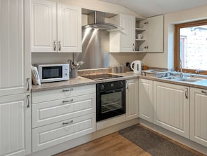 A modern kitchen with white cabinetry, a stainless steel range hood, a microwave, a kettle, and a double sink. - Ivy Cottage - UK51983 (Lancaster)