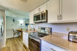 A kitchen with white cabinets, stainless steel appliances, a granite countertop, and a wooden floor. - Pool & Spa! Stylish 2nd-Floor Scottsdale Retreat (Scottsdale)