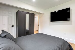 A bedroom with a bed, a wardrobe, and a television on the wall. - 2 Units: Modern Retreat w/ Deck & Workspace (Cincinnati)