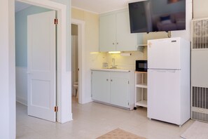 A compact kitchen with white cabinets, a built-in microwave, and a refrigerator. - Lakefront Escape at Sunrise Side Resort (Greenbush)