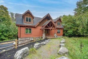 A log cabin with a stone foundation, a front porch, and a metal fence. - Game Room, Hot Tub! Retreat 3 Mi to Holiday Valley (Ellicottville)