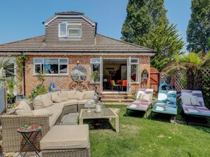 A house with a covered patio, outdoor seating, and a garden. - Boutique Gathering House (Park Gate)