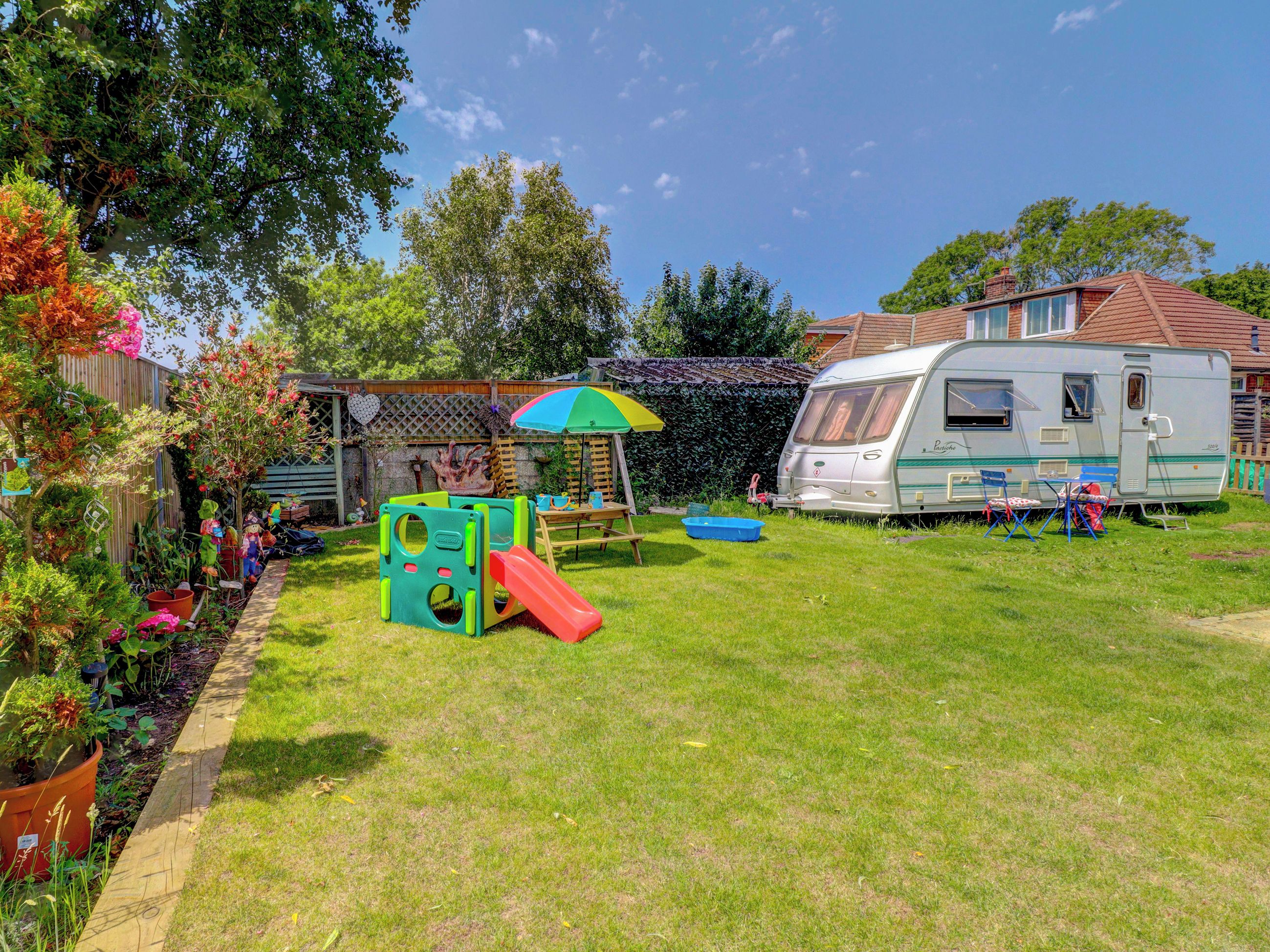 A residential property with a play area, a covered seating area, and a recreational vehicle.