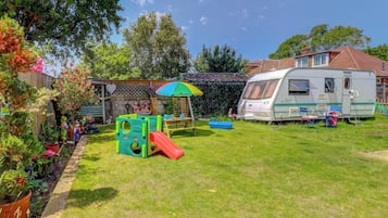 A residential property with a play area, a covered seating area, and a recreational vehicle.