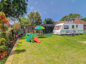 A residential property with a play area, a covered seating area, and a recreational vehicle.