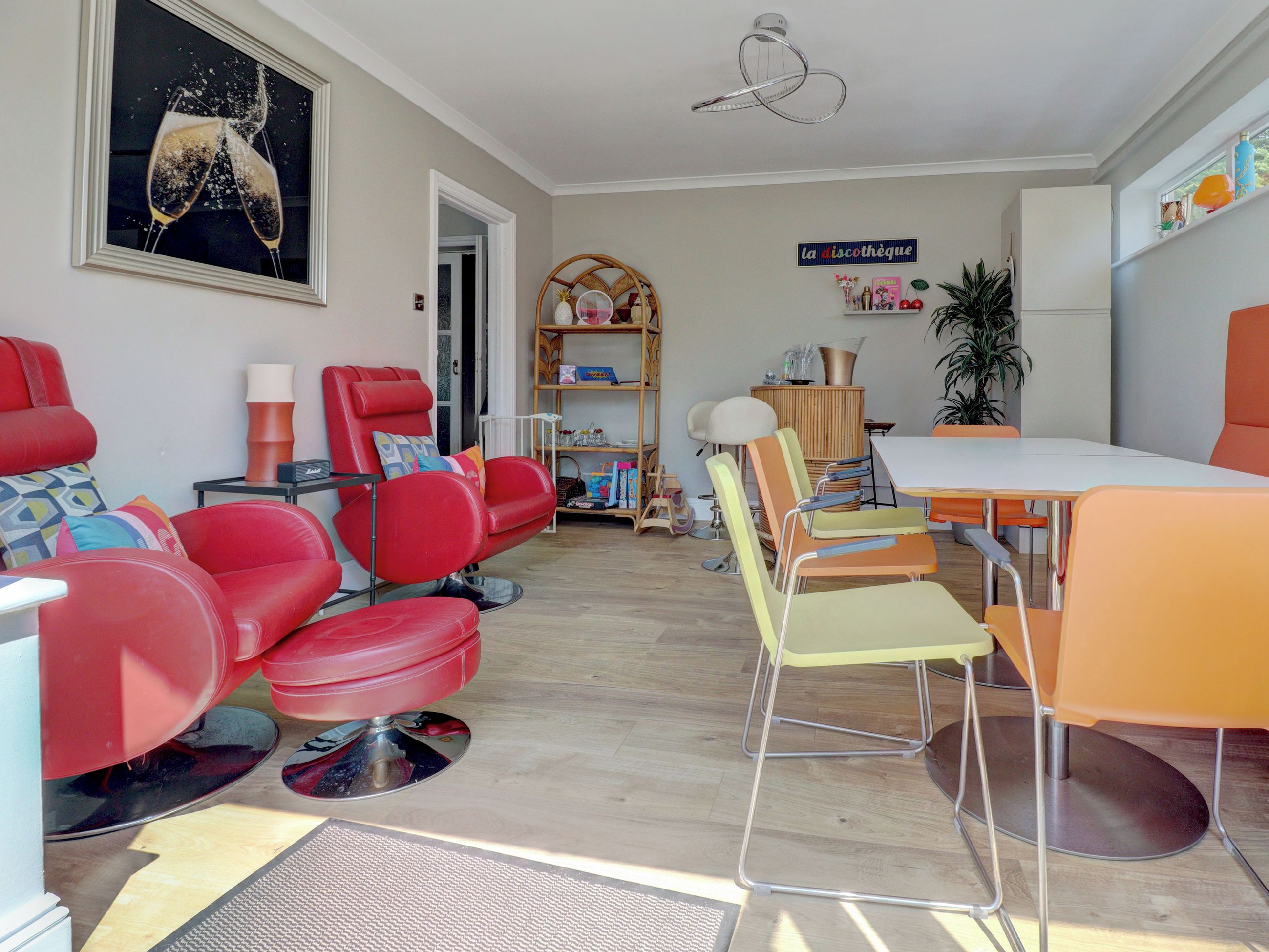 Una sala de estar moderna con sillas rojas y amarillas, una mesa de comedor y una estantería.