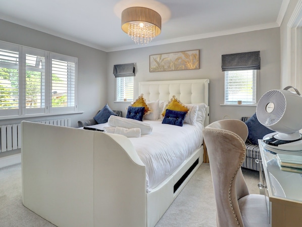 A bedroom with a bed, bedside tables, a chair, a ceiling light, and windows.