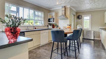 A modern kitchen with a central island, bar stools, and a clock on the wall.