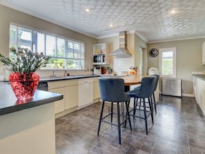 A modern kitchen with a central island, bar stools, and a clock on the wall. - Boutique Gathering House (Park Gate)