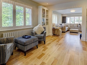 A spacious living room with striped upholstered furniture, a radiator, and large windows with shutters. - Boutique Gathering House (Park Gate)