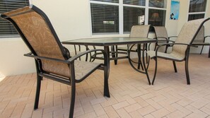A patio area with a round table and four chairs, featuring a woven seat design. - Af2568 4 Bedroom Home (Kissimmee)