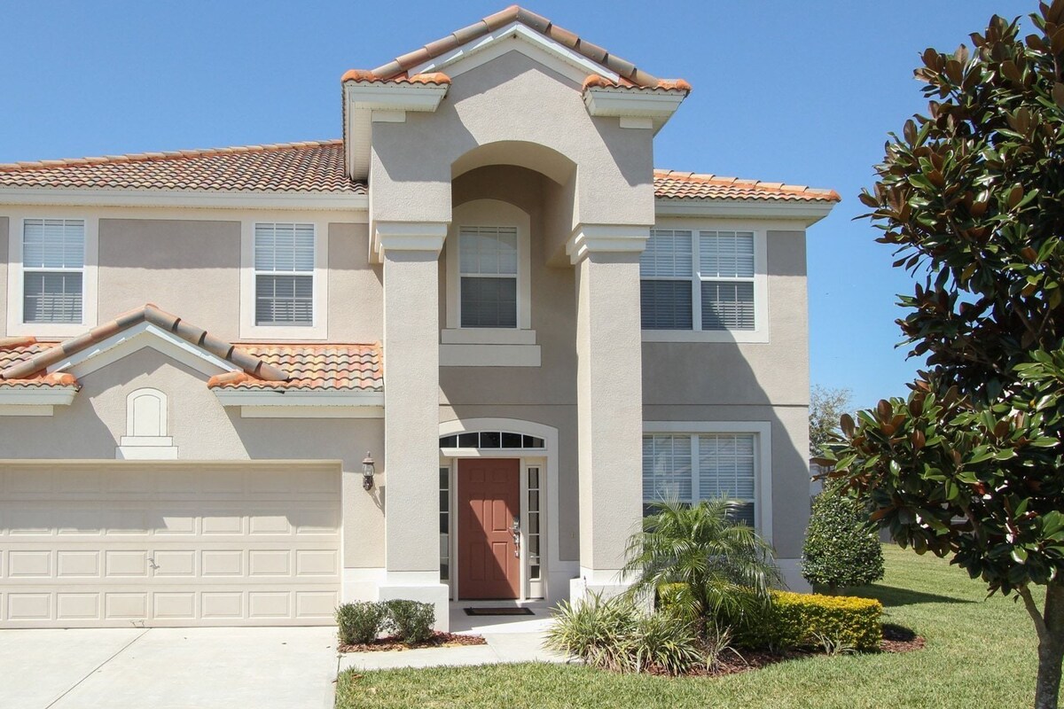 A two-story house with a garage, a central entrance, and a small front yard with landscaping.