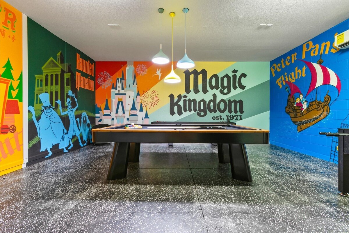 A pool table in a room with colorful murals, including one for 'Magic Kingdom' and another for 'Peter Pan'.