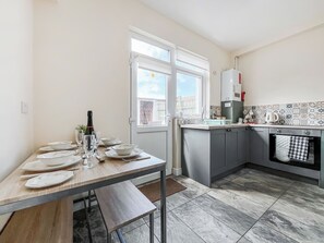 A kitchen with a dining table set for four, a window with a view, and a tiled backsplash. - 2 bedroom accommodation in Guisborough (Guisborough)