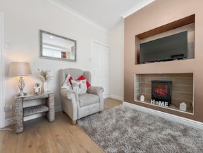A living room with a fireplace, a sofa, a lamp, and a mirror. - 2 bedroom accommodation in Guisborough (Guisborough)