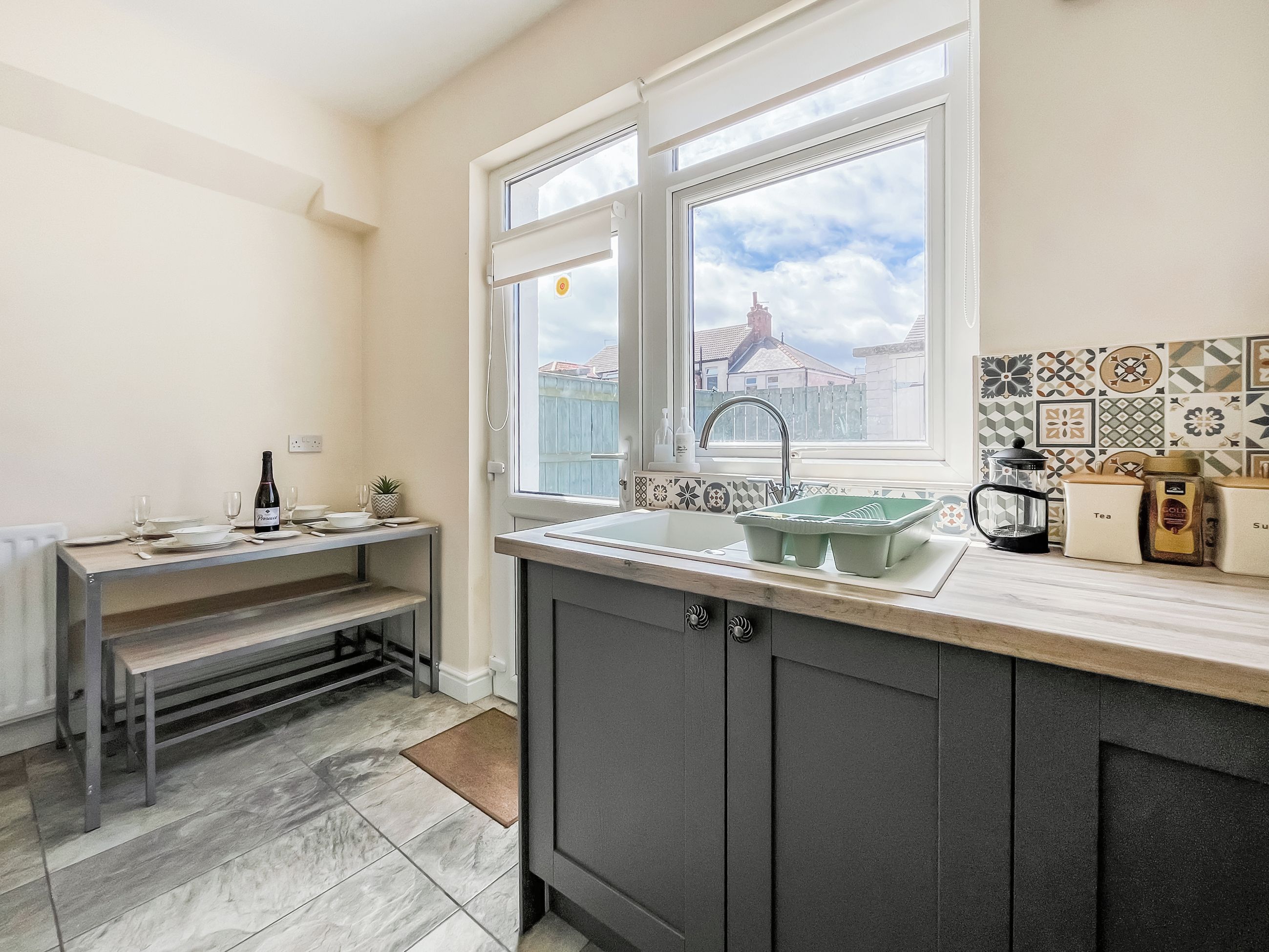 A modern kitchen with a built-in sink, a dining area with a bench, and a view of the city through a large window.