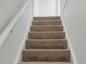 A staircase with carpeted steps leading upwards, white walls, and a handrail on the left. - 2 bedroom accommodation in Guisborough (Guisborough)