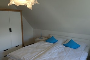 A bedroom with a bed, two pillows, a bedside table, and a wardrobe. - Thatched house "Hygge Huus" (Zierow)