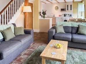 A living room with two grey sofas, a wooden coffee table with lemons, and a staircase. - The Garden House - UK52180 (Beaworthy)