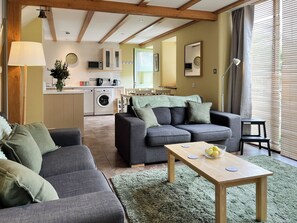 A modern living room with a grey sofa, a wooden coffee table, and a green rug. - The Garden House - UK52180 (Beaworthy)