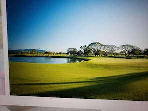 A golf course with a pond, trees, and a clear sky. - PGA golf tournament- 1 bedroom Grand Luxxe villa (Puerto Vallarta)