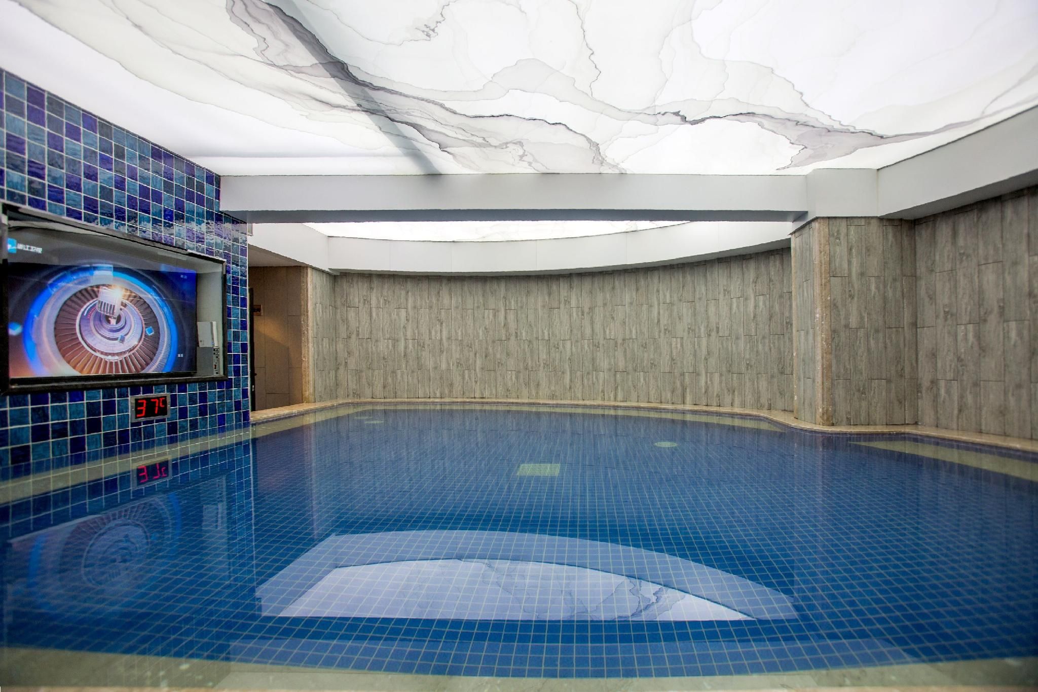 An indoor swimming pool with a digital display and a wooden wall.