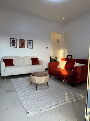 A living room with two sofas, a round coffee table, and a patterned rug. - The Ember House_Stylish 1BR apartment in kyanja. (Kampala)