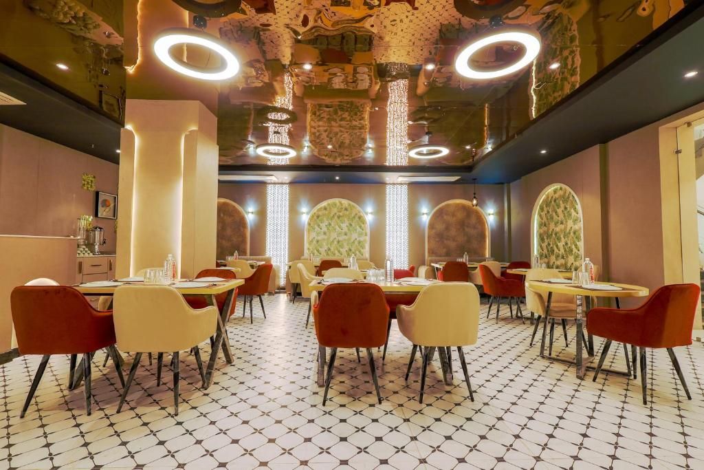 A restaurant with multiple tables and chairs, a patterned floor, and decorative ceiling elements.