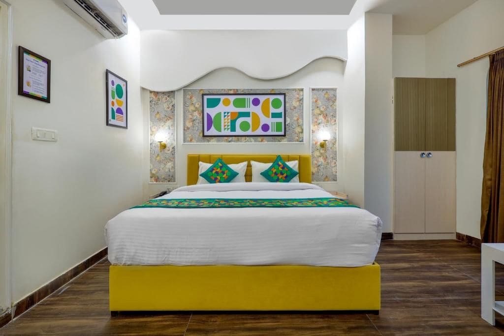 A hotel room with a bed, a headboard, a wall-mounted artwork, and a door.