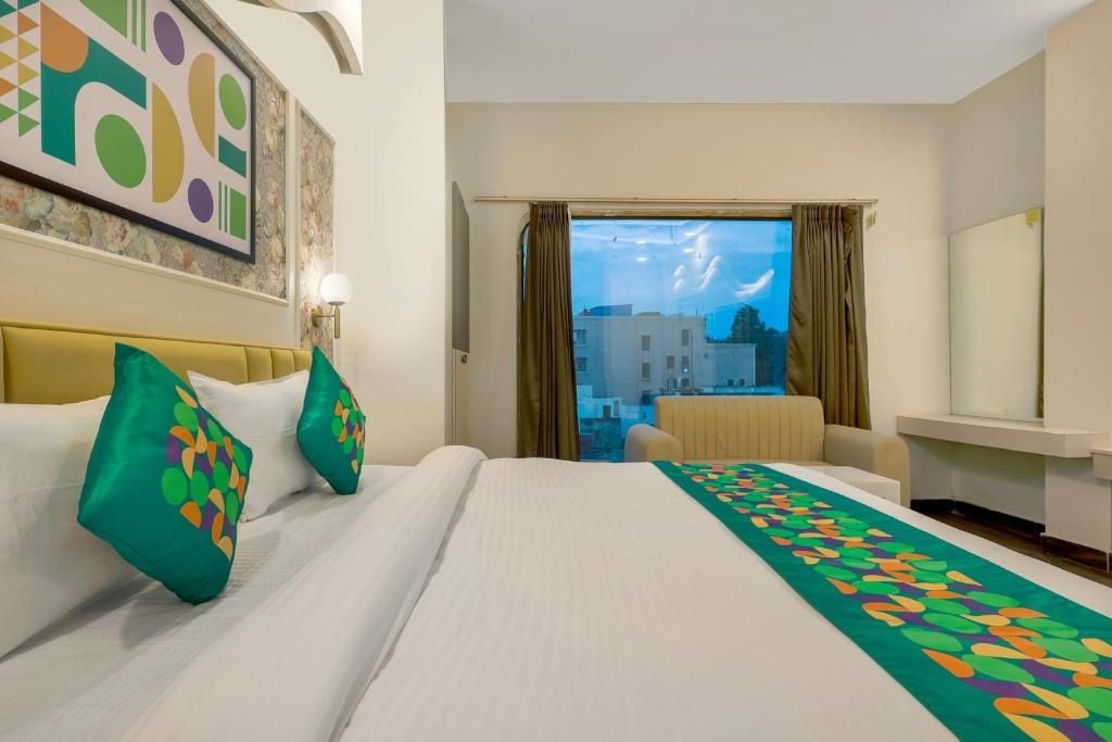 Habitación de hotel con cama, sofá, vista a edificios y un cuadro en la pared.