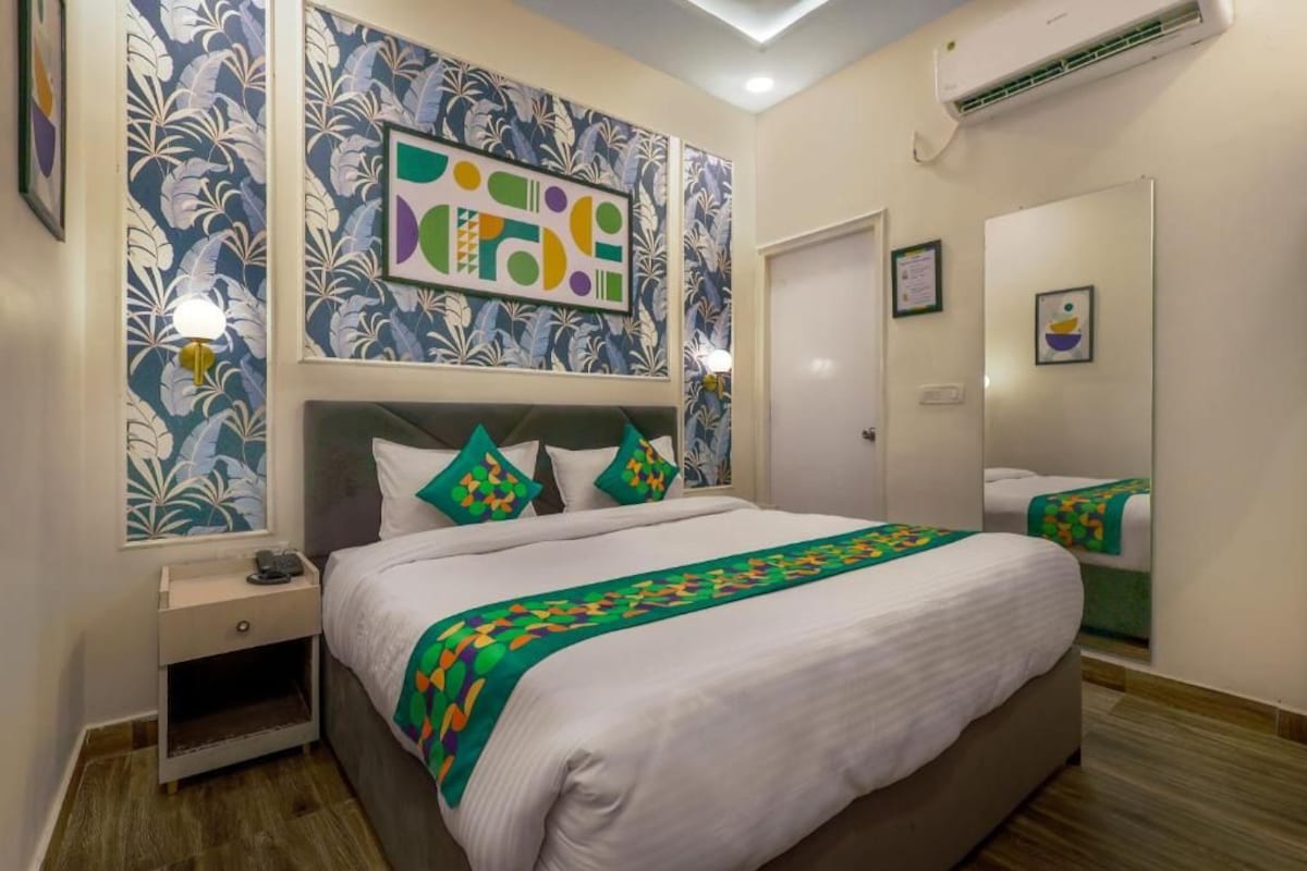 Una camera d'albergo con un letto, un comodino, opere d'arte alle pareti e un condizionatore d'aria.