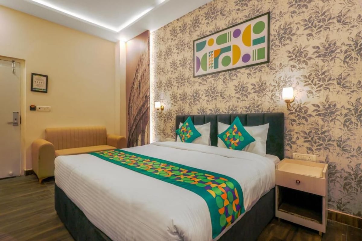 Una camera d'albergo con un letto, un comodino, una sveglia a muro e un certificato incorniciato.