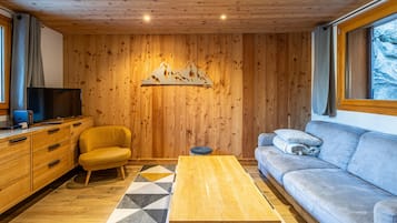 Un salon chaleureux avec des murs en bois, un canapé, une table basse et un téléviseur.