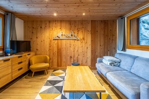 Un salon chaleureux avec des murs en bois, un canapé, une table basse et un téléviseur.