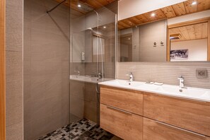 Une salle de bain moderne avec une douche à parois de verre, un meuble-lavabo en bois et un grand miroir.