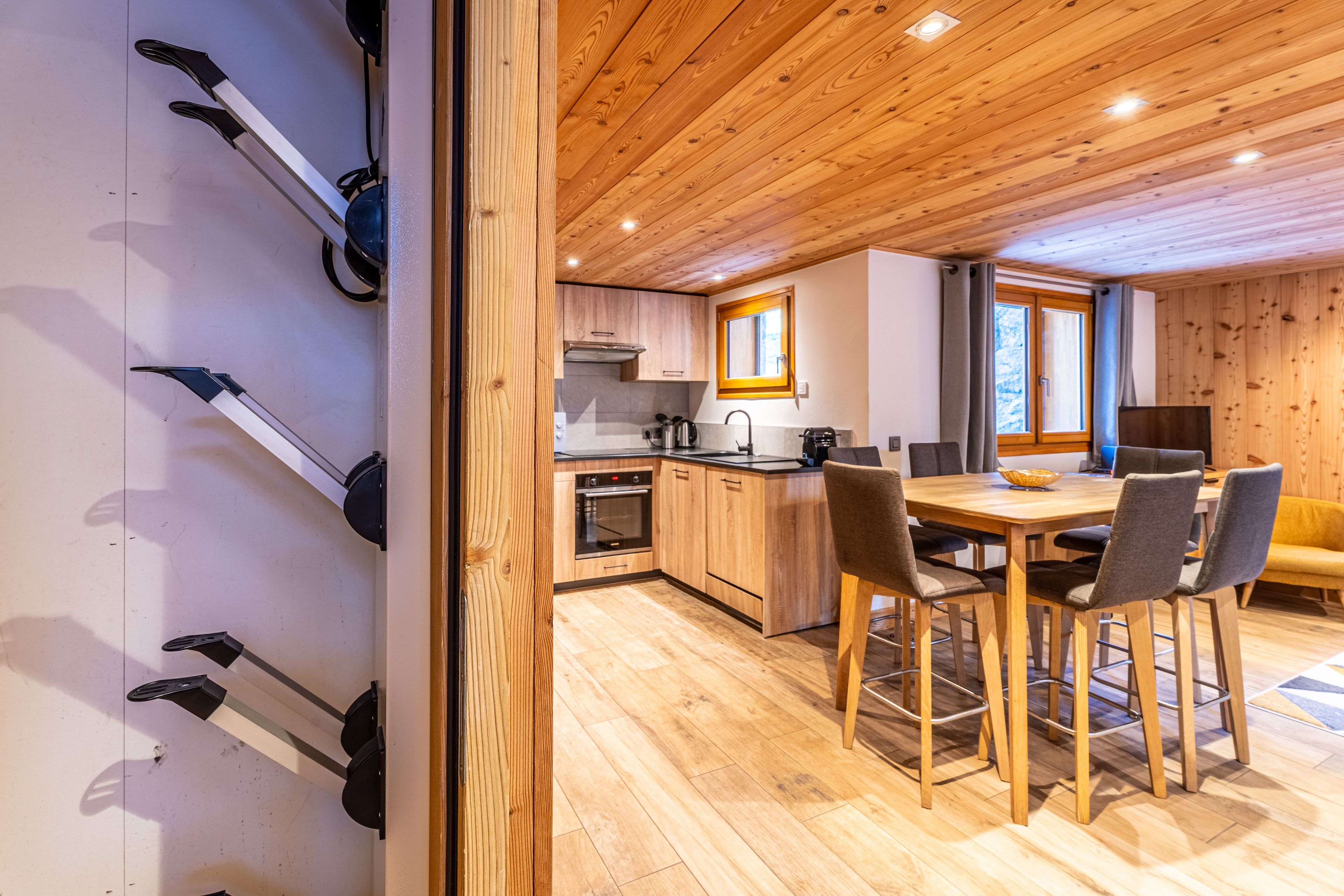 Une cuisine moderne avec des meubles en bois, un îlot central et un coin repas comprenant une table et des chaises.