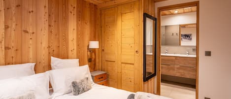 A wooden-paneled bedroom with a bed, pillows, a nightstand, and a mirror.