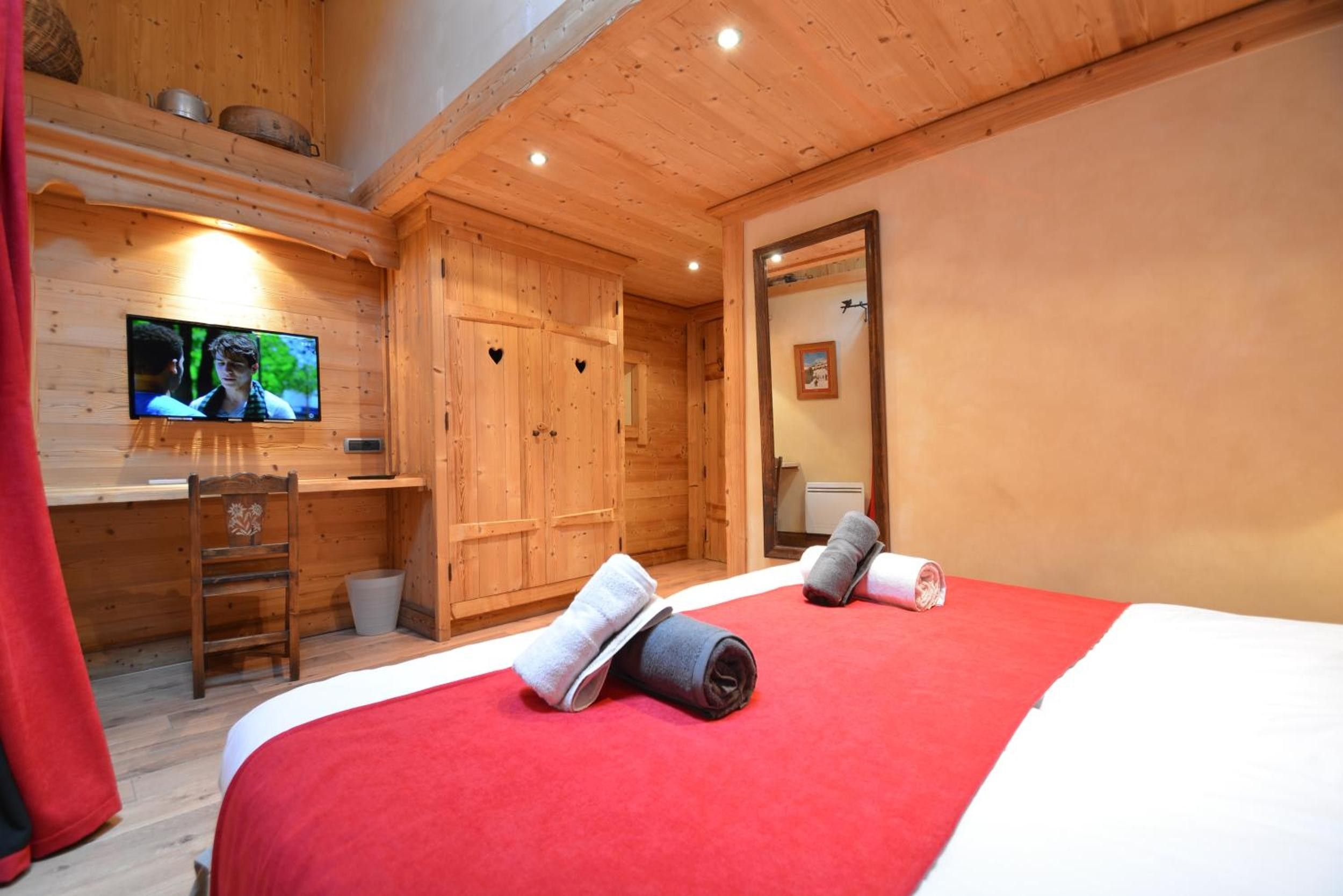 Une pièce en bois avec un lit, un bureau, une télévision et un miroir.